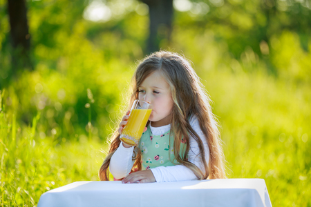Little girl drinks juice outdoorsの写真素材