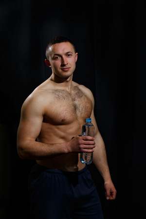 guy with a bottle of water on a black backgroundの写真素材