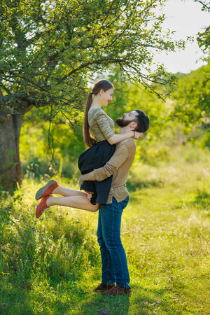 man holding his girlfriend in his arms in a summer parkの写真素材