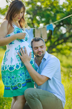 Happy expectant father listening to the belly of his pregnant wife on the natureの写真素材