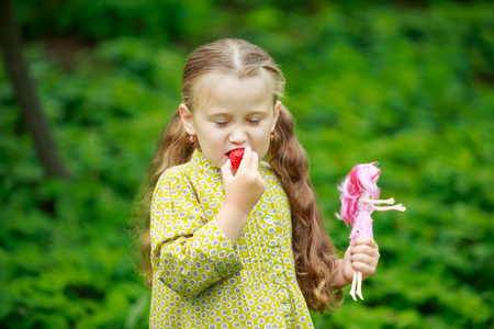 little girl eating a strawberry on the natureの写真素材