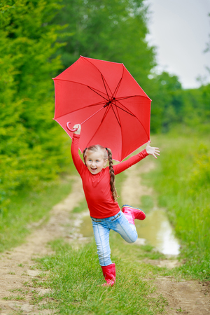 little girl with a red umbrella on the natureの写真素材