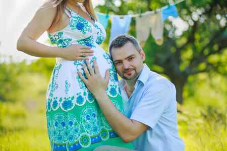 Happy expectant father listening to the belly of his pregnant wife on the natureの写真素材