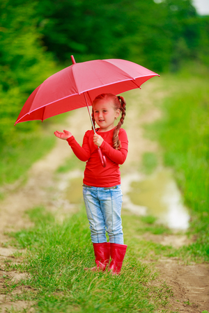 little girl with a red umbrella on the natureの写真素材