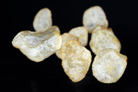 Potatoes chips flying up in the air on the black backgroundの写真素材