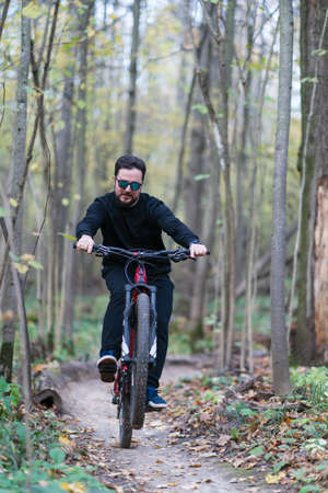A man making a trick while riding a bycicle in the autumn forestの写真素材