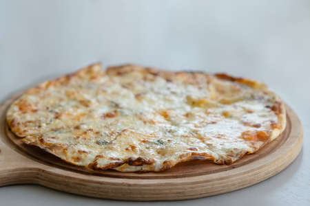 Four cheeses pizza on the wooden plateの写真素材
