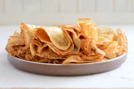 Pancakes in a plate on a light background. Shrovetide, traditional Russian cuisine