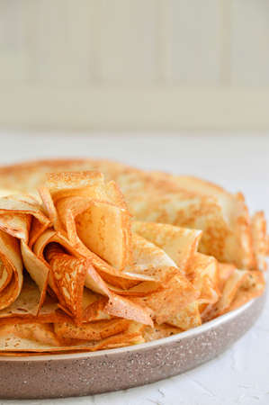 Pancakes in a plate on a light background. Shrovetide, traditional Russian cuisine