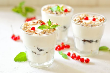 Dessert in a glass on a light background, decorated with nuts, mint leaves and berries. Creamy jelly. Parfait.の写真素材