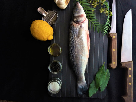 fresh fish with lemon and spices on black background