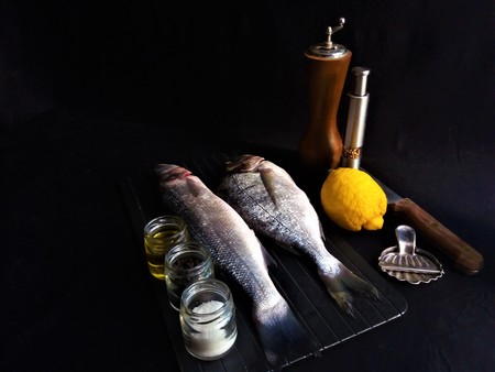 fresh fish with lemon and spices on black backgroundの写真素材