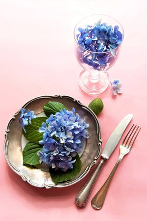View of an assortment of edible flowers with plate and fork.Edible flowers salad in a plate on rose...