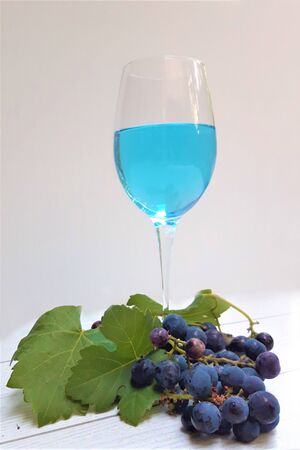 Glass of blue trandy wine with grapesの写真素材