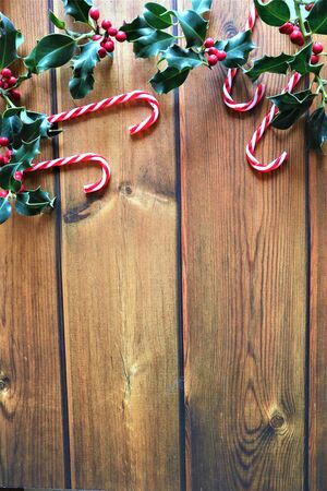 Christmas Background. Composition with red berries, holly leafs and berries, balls, pine cones, Christmas decoration on wooden background. 
Merry Christmas composition, New Year bauble on winter background. Flat lay, top view, copy space.の写真素材