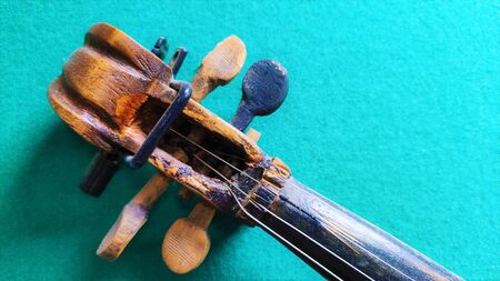 violin in vintage style on green backgroundAn old violin, close up of the head on green background