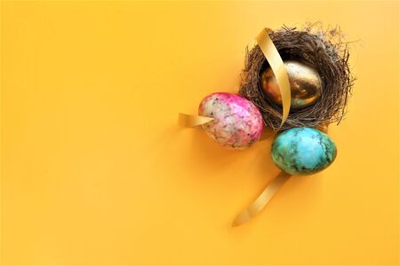 golden colored easter eggs on yellow background copyspace