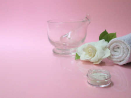 Spa setting and Spa background composition with white gardenia flower on pink background. Towel, candles, flowers, stones. Massage, oriental therapy, wellbeing and meditation.の写真素材