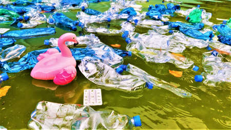 pollution of the environment. plastic bottles in water and inflatable toys. Inflatable pink flamingos among plastic garbage. bannerの写真素材