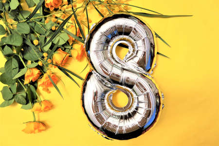 March 8, yellow mimosa and roses on a yellow background. copy space. flat lay