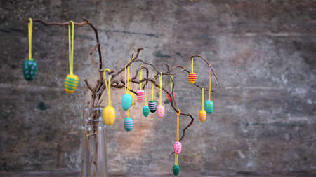 Easter dekorative eggs on tree branches. Easter tree in vase with colorful eggs on a gray rustic...