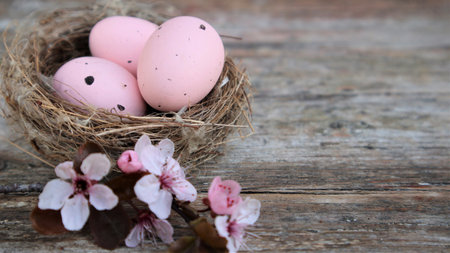 Easter eggs in nest and pink flowering sakura branches on rustic background. Happy Easter holiday....