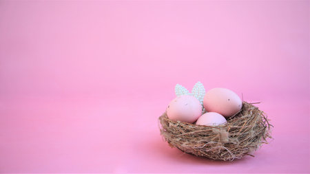 Easter composition with eggs and rabbit ears made of small pearls on pink pastel background. Happy easter. Copy spaceの写真素材