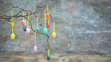 Easter decorative eggs on tree branches. Easter tree in vase with colorful eggs on a gray rustic...
