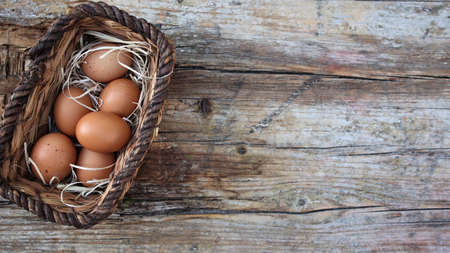 background easter. A basket with eggs stands on a wooden rustic background. copyspace. flat lay. top...