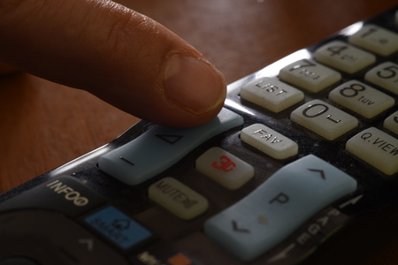 TV remote control with finger on the volume