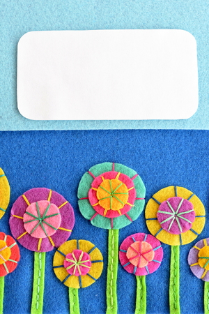Mixed felt flowers on blue background with blank place for text. Variegated flower embroidery for kids. Floral greeting card for holiday, birthday, Easter, Valentine's day, mother's dayの写真素材
