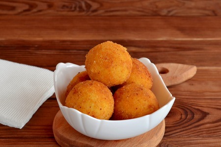 Arancini balls on a plate. Fried rice cutlets recipe. Brown wooden backgroundの写真素材