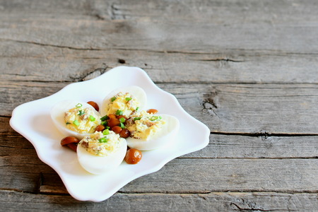 Classic stuffed eggs on a plate isolated on old wooden background with copy space for text....