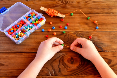 Children hands holding beads and cord. Baby sensory gameの写真素材