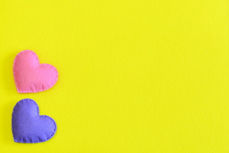 Two felt hearts isolated on yellow background with copy space for text. Valentine's day, wedding or mother's day background or card. Handmade felt hearts decorations. Top viewの写真素材