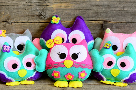 Nice kids felt toys. Colored stuffed owls toys on vintage wooden background. Decorations crafts made of felt. Fun kids background. Closeupの写真素材