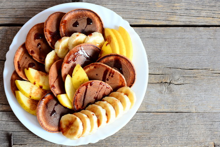Chocolate pancakes with fresh fruit. Baked chocolate pancakes with syrup, sliced ??bananas and...