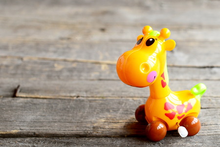 Mechanical wind up plastic giraffe toy. Pretty clockwork children toy isolated on old wooden background. Fun children backgroundの写真素材