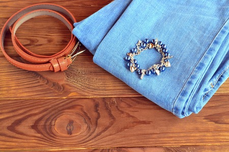 Jeans, bracelet, belt on wooden background with copy space for textの写真素材