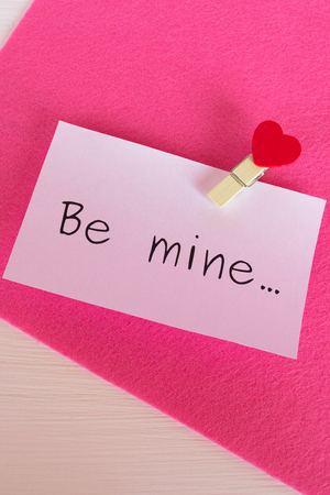 Words "be mine" isolated on pink and white wooden backgroundの写真素材