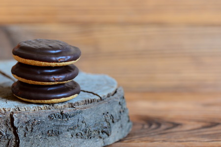 Cookie stack on a wooden background with copy space for text. Three round biscuits in chocolate...