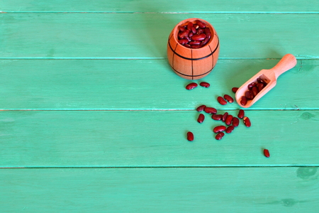 Raw red beans in a small barrel and a wooden scoop on a green backgroundの写真素材