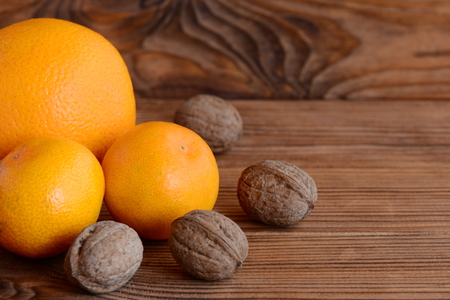 Mandarin, orange, walnuts on a wooden table. Natural sources of vitamins and minerals. Healthy eating. Brown wooden background with copy space for textの写真素材