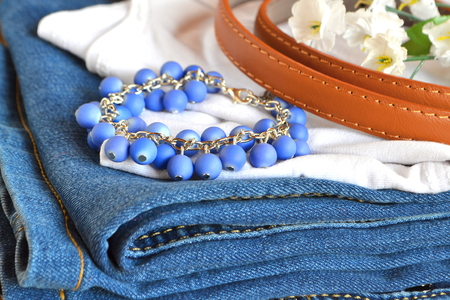 Jeans, white t-shirt, brown belt on a wooden background. Women clothes set. Close upの写真素材