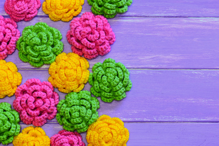 Crocheted roses. Yellow, pink and green crocheted roses. Colorful floral decorations on a wooden background with copy space for text. Top viewの写真素材