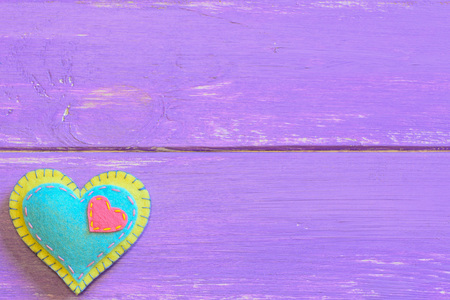 Felt heart isolated on a purple wooden background with copy space for text. Felt valentine. St....
