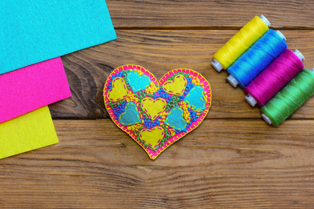 Valentines Day heart symbol. Colorful felt heart, thread set, felt sheets on a wooden table. Top...