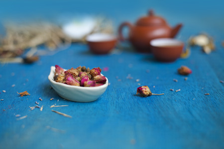 Rose buds on a plate with teapot and two cups. Focus on a plate.の写真素材