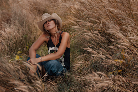 attractive boho woman sitting on meadow outdoorsの写真素材