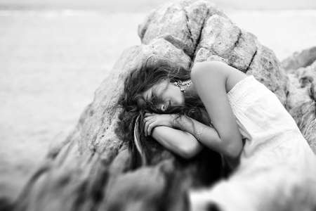 beautiful young woman sleep on the rocks at the beachの写真素材